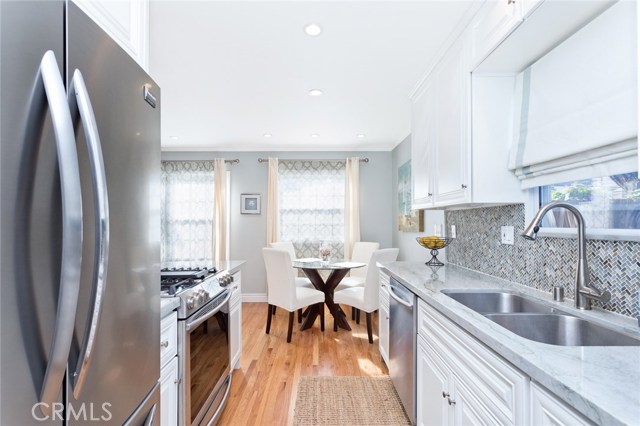 Stainless appliances, white wood cabinets and a bright eating area.