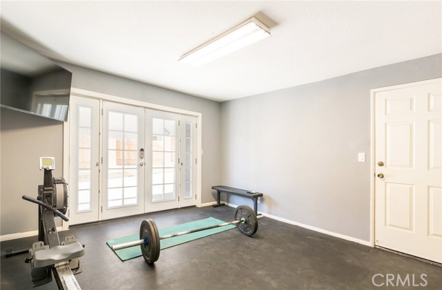 5th bedroom currently being used as home gym with french doors opening up to small patio outside