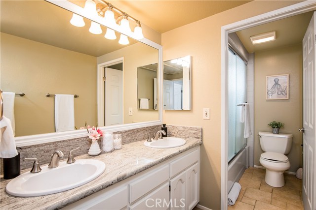Master bathroom with double sinks, separate toilet and shower tub area, and cabinets for additional storage