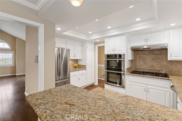 Open concept kitchen with stainless steel appliances and beautiful travertine back splash.