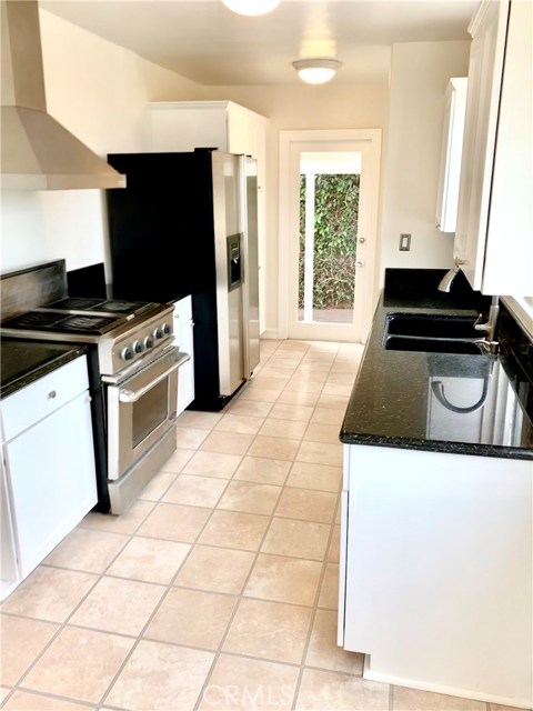 Kitchen has freshly painted hardwood cabinets and new light fixtures.