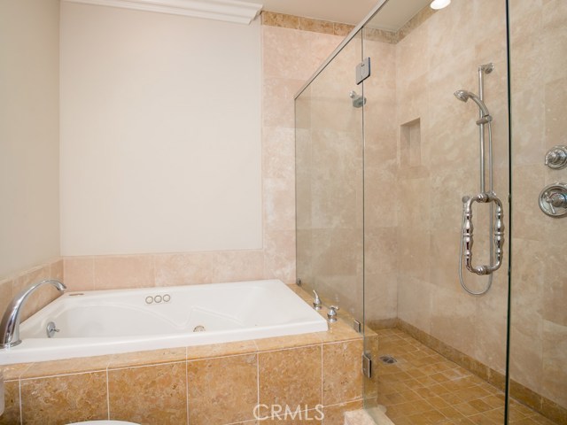 Grand ensuite featuring double sinks, decorative tile back splash, separate tub and extra-large frameless shower