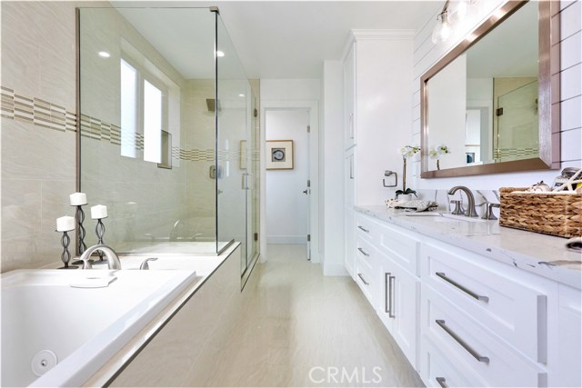The Master Bathroom has a Large Jacuzzi Tub and Shower with Custom Tile and Glass Trim Accents, a Seamless Glass Enclosure, Porcelain Wall and Floor Tile, a Dual Sink Vanity with Self-closing Drawers and Cabinet Doors, a Thick Slab Misty White Carrara Caesarstone Counter Surface, Moen or Kohler Fixtures, Custom Lighting, Pebble Stone Shower Floor andHorizontal Planked Shiplap Walls.