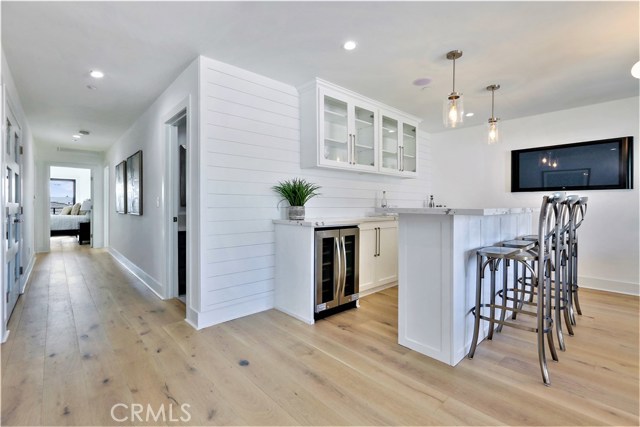 At the top of the stairway on the second floor is the Bar/Den/Game Room. This area features a Large Entertaining Bar, Thick Slab Misty White Carrara Caesarstone Counter Surface, 2 Insignia Refrigerated Double Door Wine Cellars, Horizontal Planked Shiplap Siding, Custom lighting and 2 large siding doors which open to and Ocean View Balcony & Stairway leading up to the Huge Roof Deck