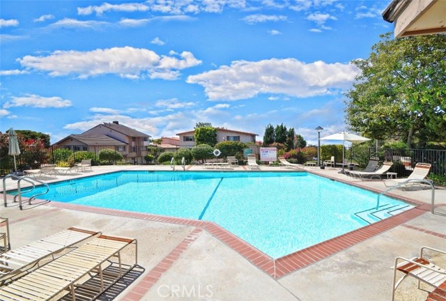 Large and inviting pool area with lounges and umbrellas with some ocean views.