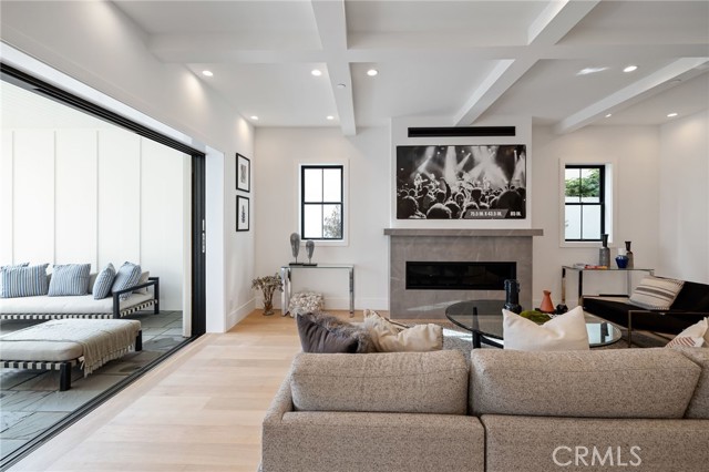 Coffered ceilings, stylish fireplace, and disappearing glass doors all harmonizing