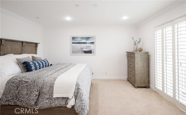 Large window plus balcony plus recessed lighting create warm and bright primary bedroom.