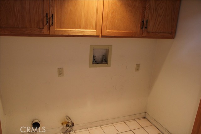 Large laundry room with washer and dryer hookups off of the garage entrance. Additional storage up top.