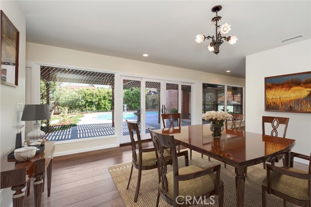 Spacious formal dining room overlooks pool and patio on one side and lush grassy area on the other side; new windows, doors and wood floors make everything crisp and clean