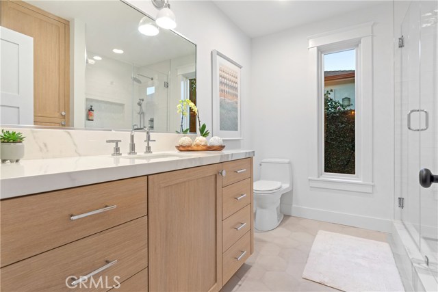 The gorgeous spa-like bathroom with custom Field Tile in White from Mission Tile West on shower walls,
Chevron Glass Tile by Artistic Tile, Swingin’ Chevron Be Bop White Glass Mosaic on niche
Calacatta Gold Broken Joint Mosaic polished stone by Artistic Tile on shower floors, with Laverton Nieve hexagon tiles on bathroom flooring, and Rift white oak vanity and custom cabinet by Coastal Cabinets.