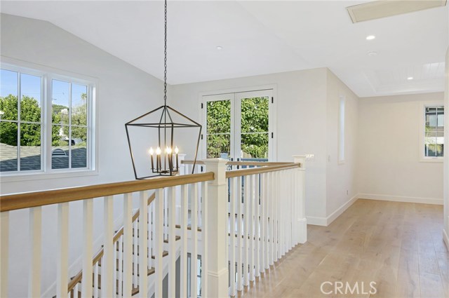 Staircase open to below and a view into the upstairs bonus room with tongue and groove ceiling.