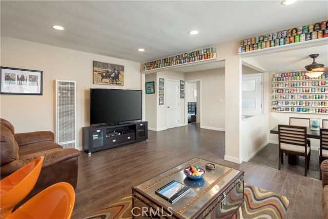 The living room is a bright an open space with wood-style floors, recessed lighting, and plantation shutters.