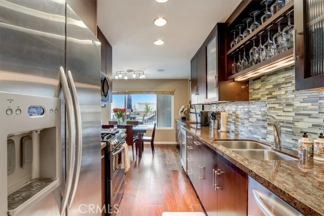 Great long and open kitchen space w/wine glass overhead holder, granite counters, double sink and glass mosaic back splash!