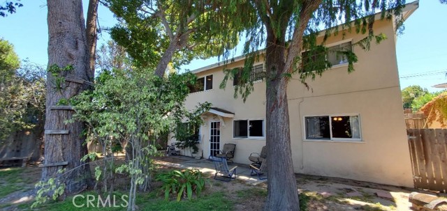 Patio and back of home with mature trees.