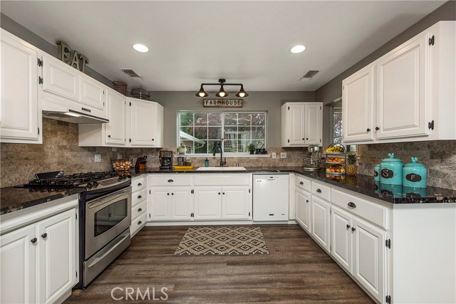 Kitchen with pullout in cabinets, stainless steel range, oil-rubbed fixtures & granite slab counters