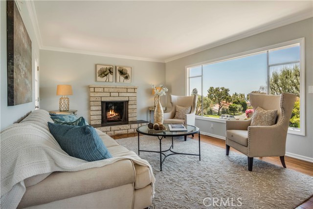 Living room with wood burning fireplace, hardwood floors and a distance ocean view out the large picture window