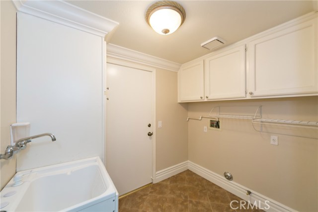 Individual laundry room with sink, cabinets & hanging racks