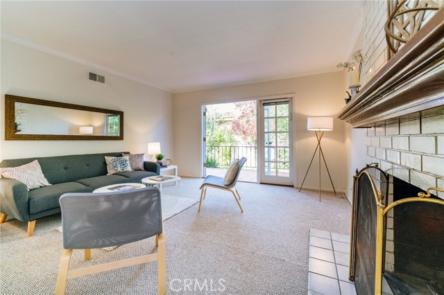 The living room with warm fireplace overlooks the Spanish-tiled veranda and the lush and tranquil backyard.