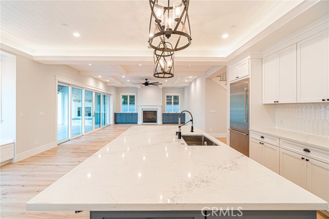 View of kitchen island and family room as well as 20 foot multi-sliding door that leads to covered backyard patio area.