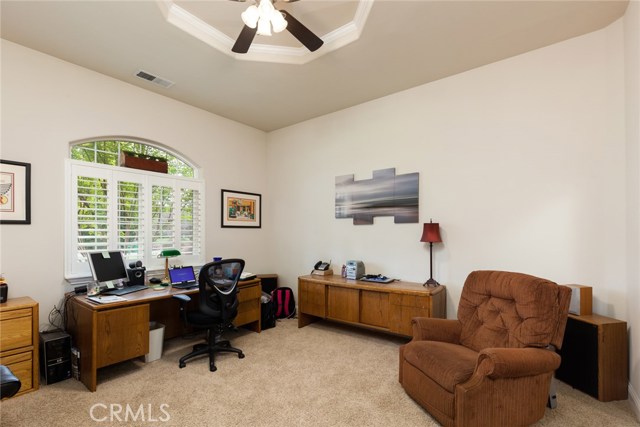 Bedroom with plantation shutters, ceiling fan.