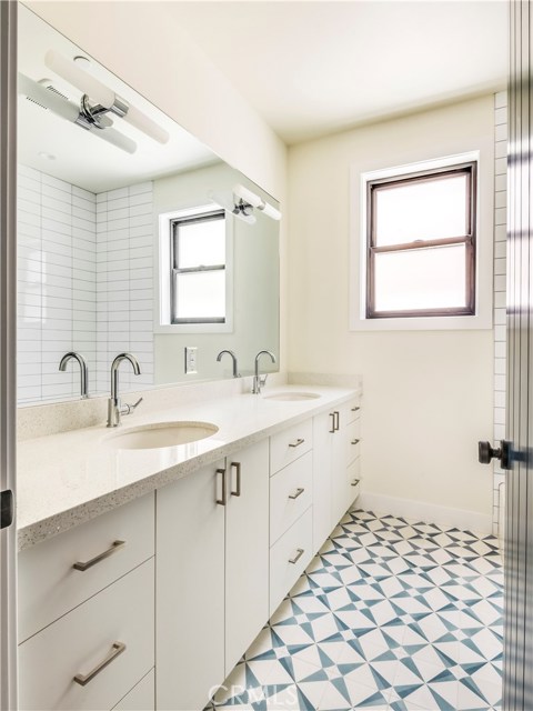 Downstairs bathroom with double sinks, designer cement Spanish style tiles, and cast iron Kohler tub