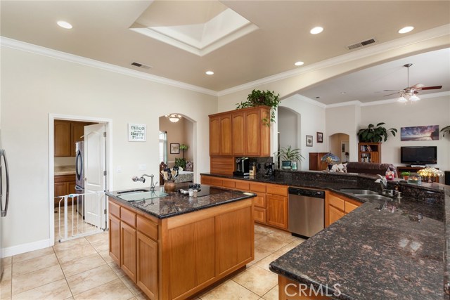 Kitchen with granite counter tops, recess lighting, custom cherry cabinetry, stainless steel appliances, eating bar, island, skylight, tile floors.