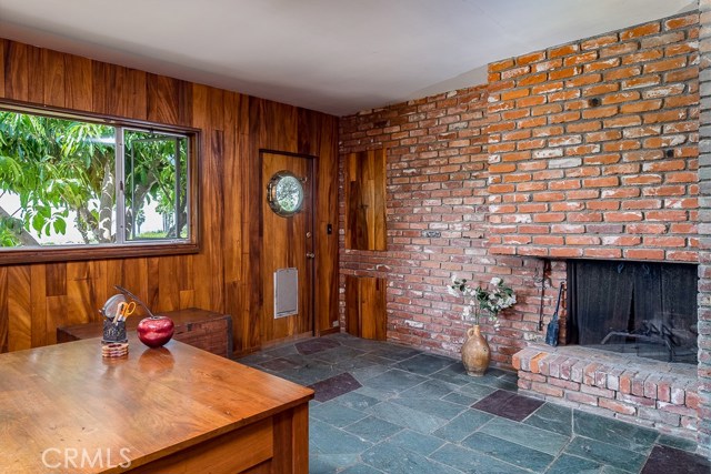 Den with slate floors, fireplace and wood paneling.