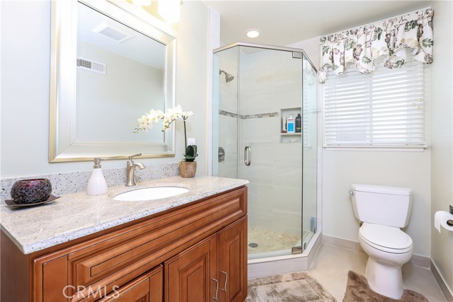 Guest bathroom, with granite counter, nice wooden vanity, tile shower with designer touches