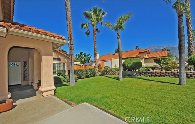 Manicured lawn, palm trees, mountain view and covered entryway