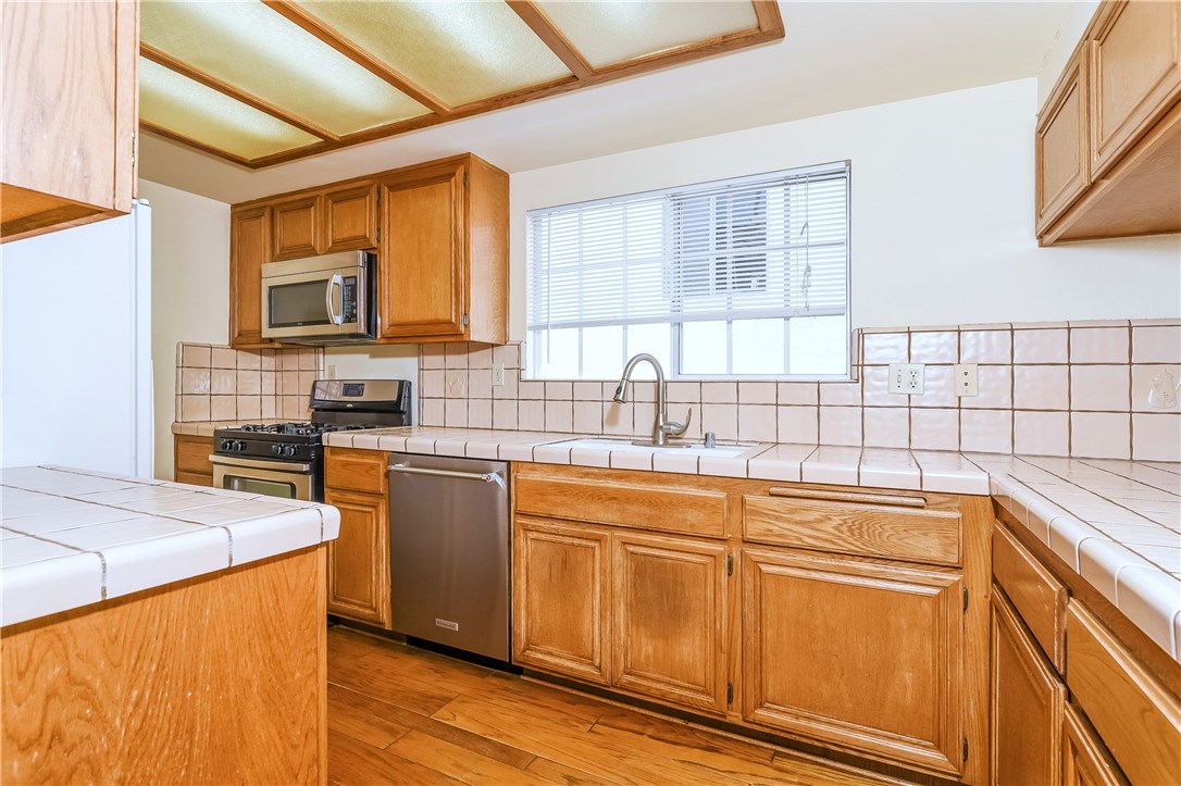 The kitchen has hardwood floors, lots of counter surfaces and great storage in the wooden cabinets, which includes an ample pantry.