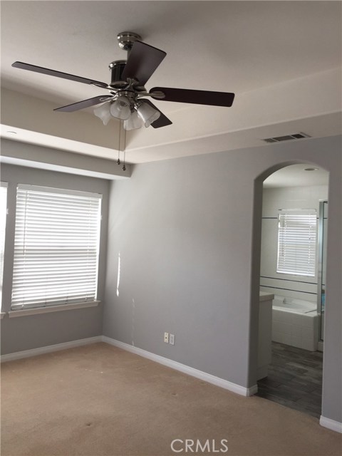 Master bedroom with arched door, tray ceiling and fan leads to en suite bath ....