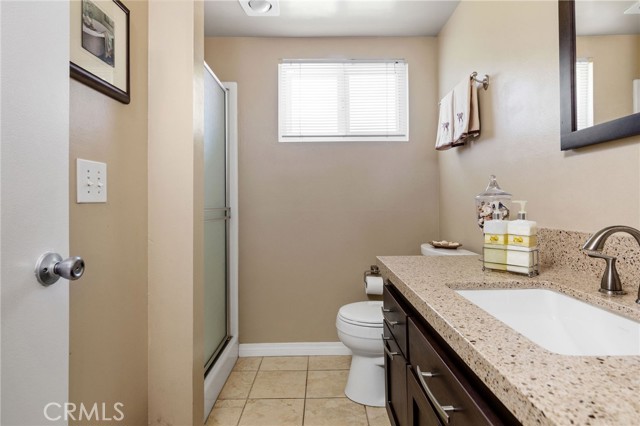 Remodeled bathroom has quartz counter and tile flooring.