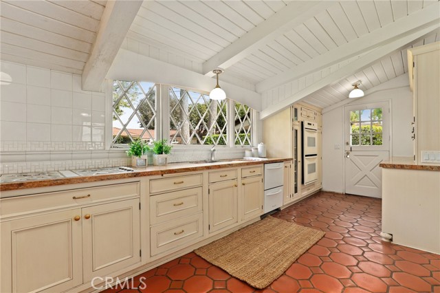 Another kitchen shot showing the double oven, custom cabinetry and dutch door in back ground to the driveway.