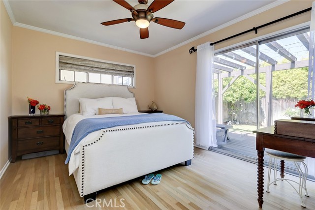 The primary bedroom with hardwood floors features an oversized sliding glass door that opens to the secluded, private garden.