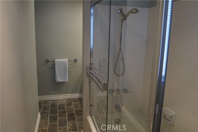 Third bathroom with glass enclosure around tub and shower. Slate floors.