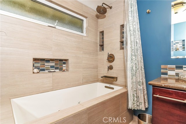 The jacuzzi tub has a seating area deck. waterfall faucet, rain fixture and there are nice glass tile accents