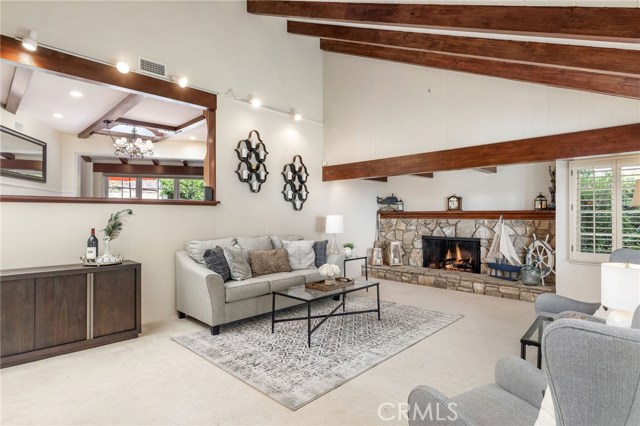 The living room features a large and inviting warm fireplace, exposed rich wood beam ceiling, and the open style space adds to the highlights of the home.