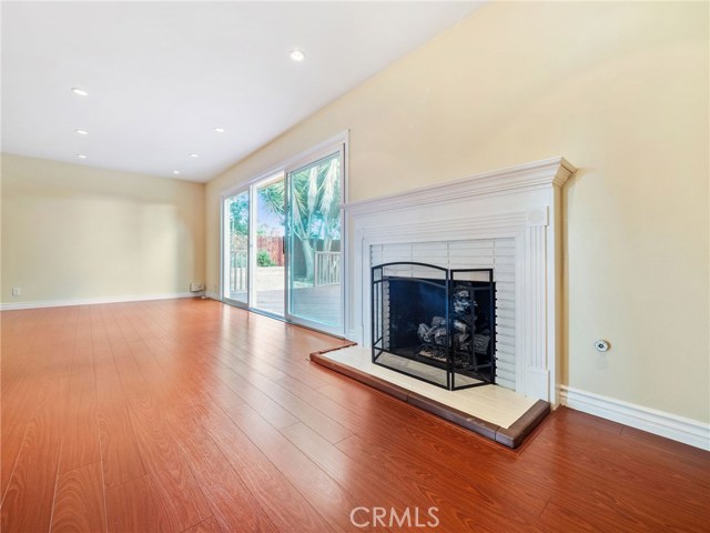 The welcoming and spacious living room is highlighted by a fireplace and view of the backyard and features recessed lighting and hardwood floors.