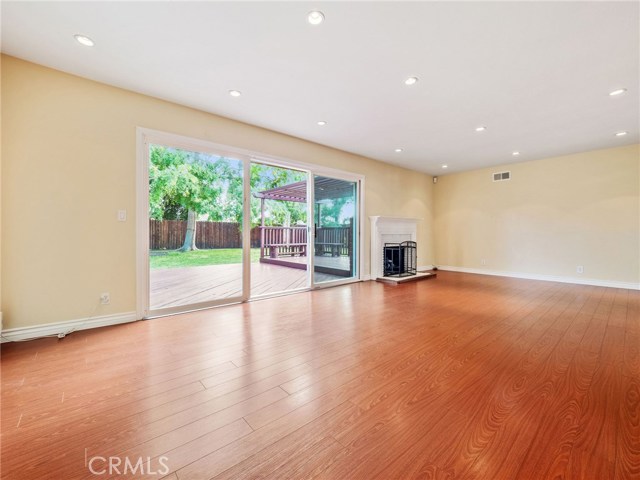 The welcoming and spacious living room is highlighted by a fireplace and view of the backyard and features recessed lighting and hardwood floors.