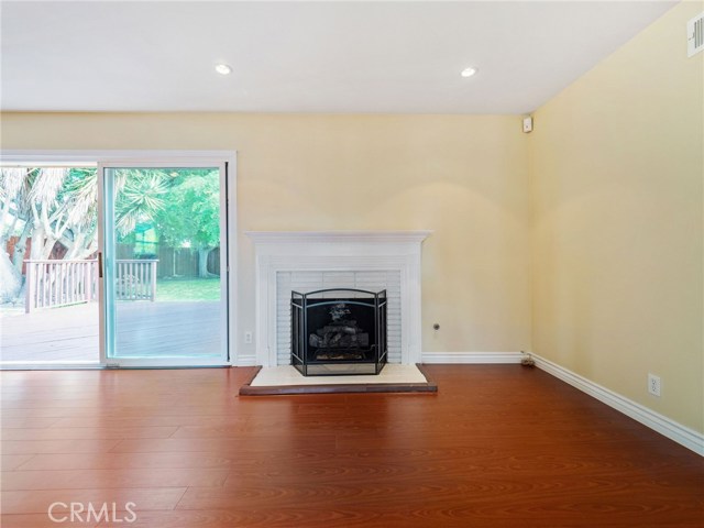 The welcoming and spacious living room is highlighted by a fireplace and view of the backyard and features recessed lighting and hardwood floors.