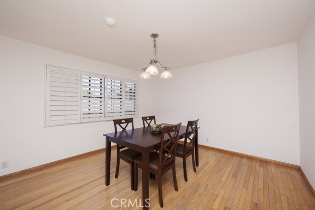 Dining room with hardwood floors, chandelier and plantation shutters.