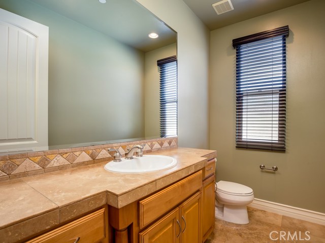 Second story guest bath with stone floors and counters and maple cabinetry.