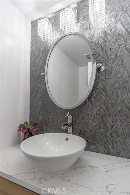 Updated modern half bath with marble counter, vessel sink, smart shimmering designed tiles