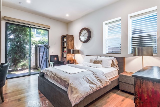 Ground floor guest bedroom with hardwood floors, voice controlled shades and lighting, and sliders to the side patio