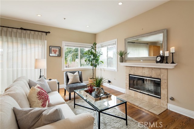 The living room features warm natural oak hardwood floors, gas fireplace, recessed lights, and pre-wired for media above the fireplace.