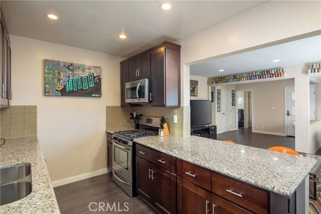 The gorgeous kitchen with newer stainless steel appliances, rich wood cabinetry, granite counter tops, and glass tiled backsplash.