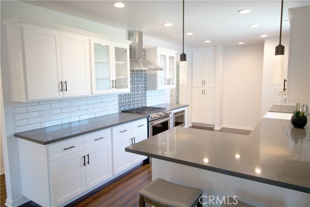 Kitchen boasts white cabinetry w/self-closing drawers & doors, gray quartz counter-tops, Kitchen Aid appliances/including microwave drawer, gorgeous large farm sink, recessed lighting, decorative tiles w/Spanish flair over stove and an Island area which opens to the dining room.