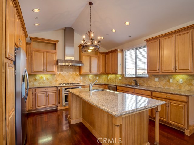 Large island in kitchen has additional sink.  Kitchen is well lit with recessed lighting, under cabinet lights, and dramatic fixture.