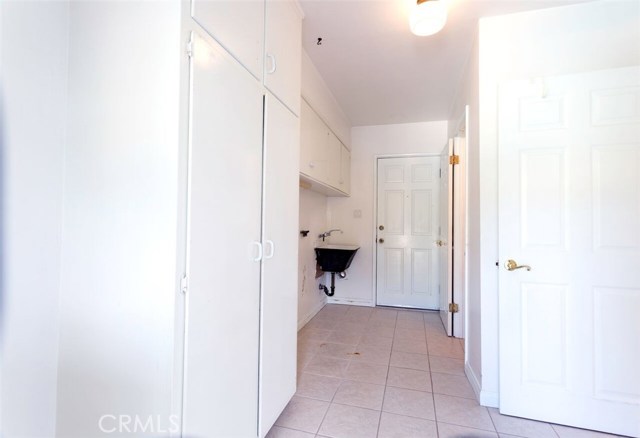 Laundry room just off kitchen with sink and lots of additional storage.