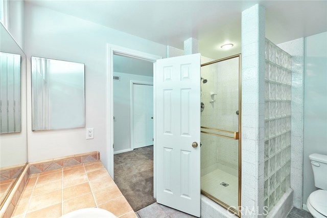 Master shower with sink and door to dressing area and closet
